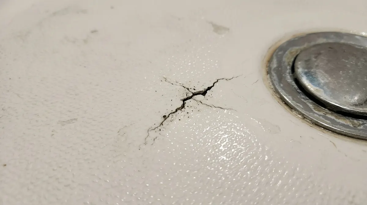 Crack in a white fiberglass shower floor near the drain
