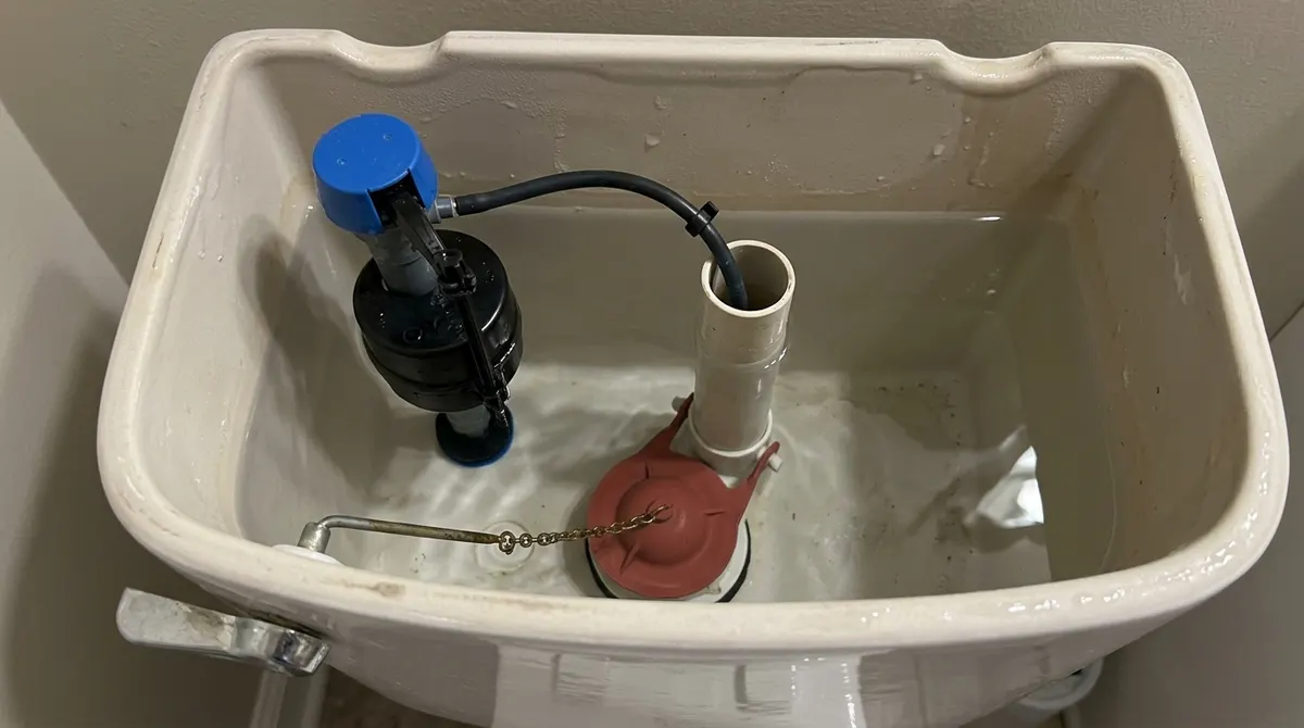 Open toilet tank showing the fill valve, float and overflow tube